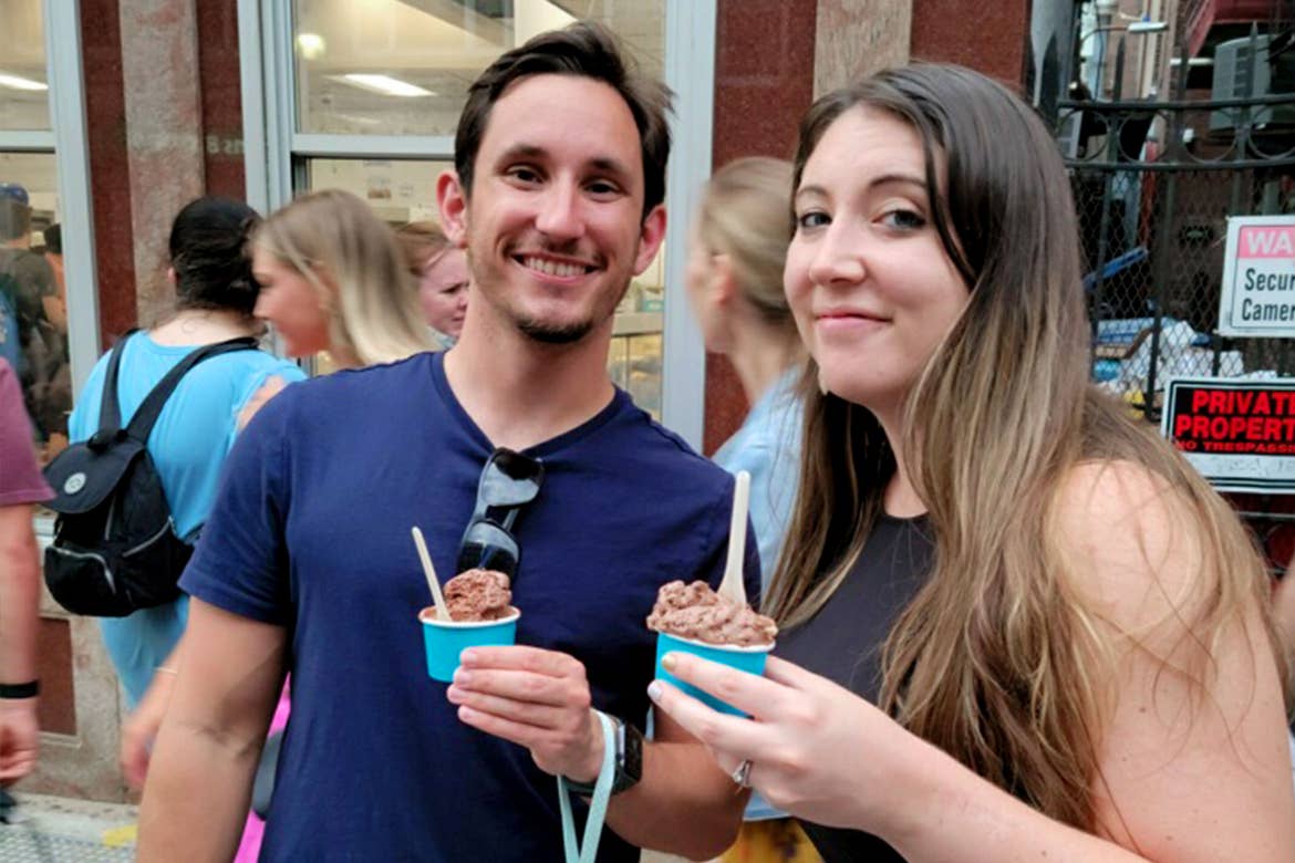 A man (left) and woman (right) hold cups of gelato outside a storefront.