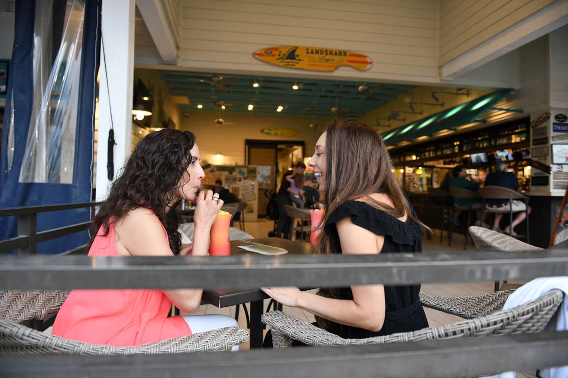 Raff and her wife enjoying fruity cocktail drinks at Breezes Restaurant & Bar at Orange Lake Resort