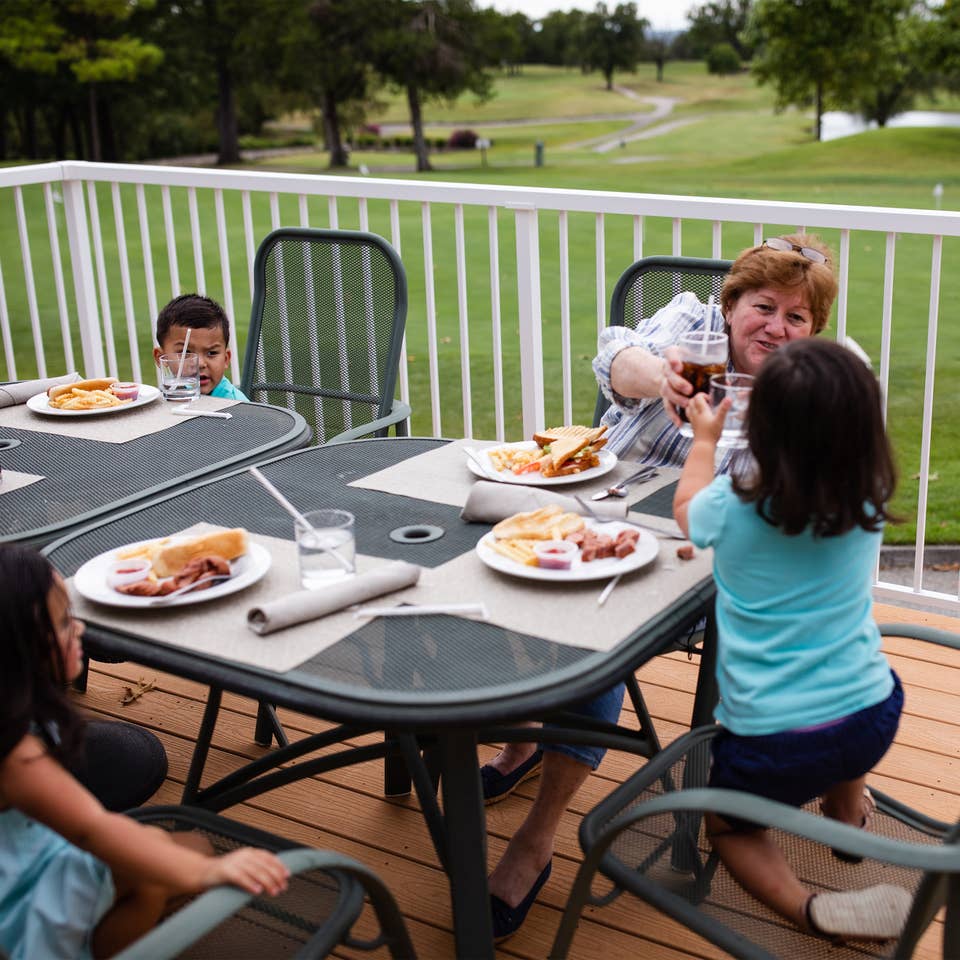 Family eating outdoors at The Grille on the Greens at Holiday Hills Resort in Branson, Missouri.