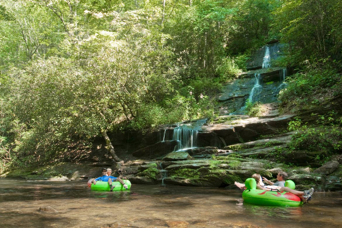 A family tubing down a river past a waterfall.