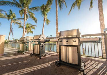 Outdoor grilling area with three stainless steel grills at Sunset Cove Resort in Marco Island, Florida.
