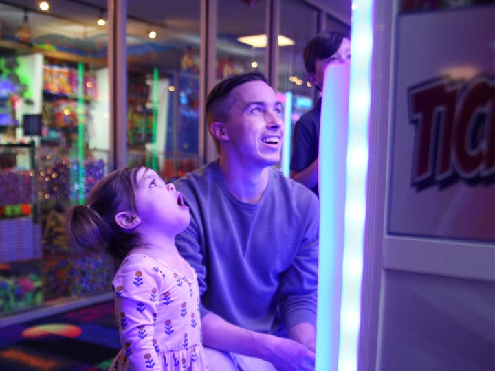 A young man and toddler girl playing video games in a game room.