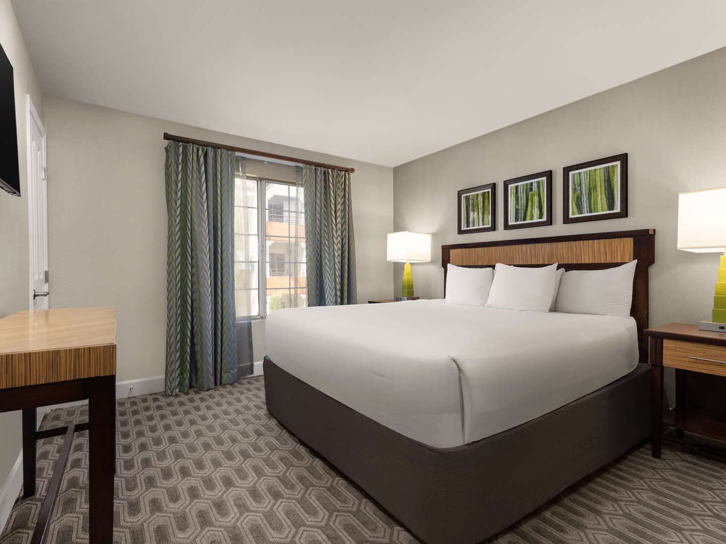 Bright, modern bedroom featuring a plush king bed and warm accents.
