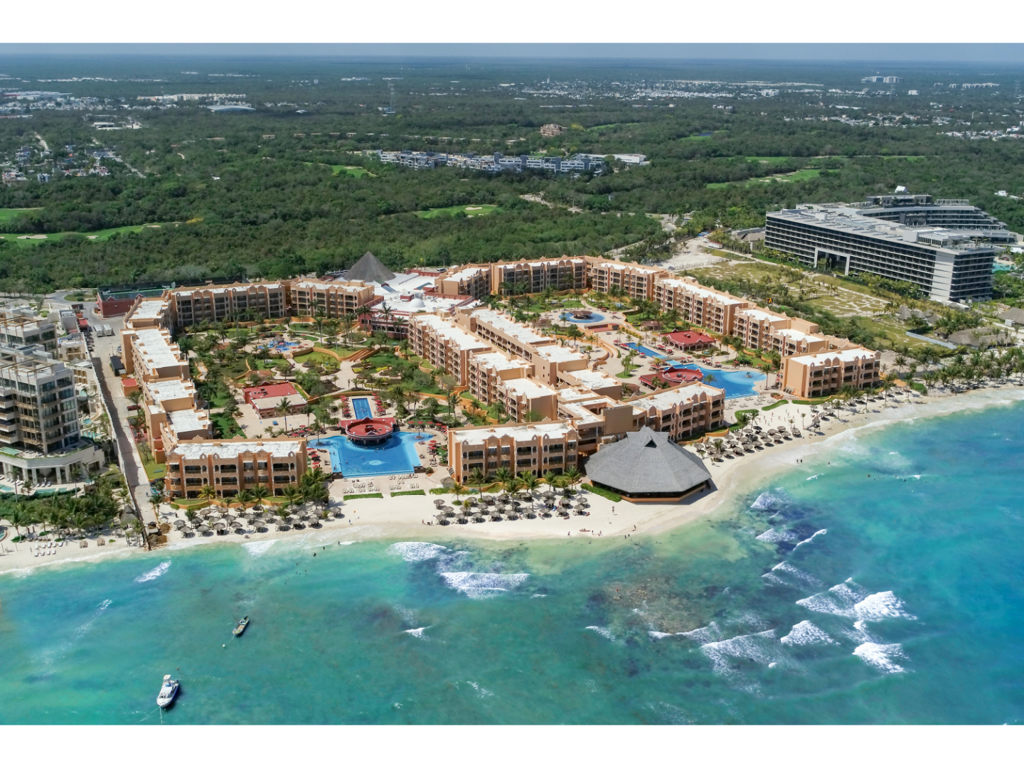 Aerial view of coastline with lrge, busy resorts and green vegetation.