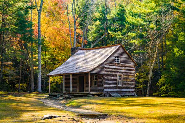 A log cabin surrounded by fall foliage in the forest of Cades Cove in the Smoky Mountains