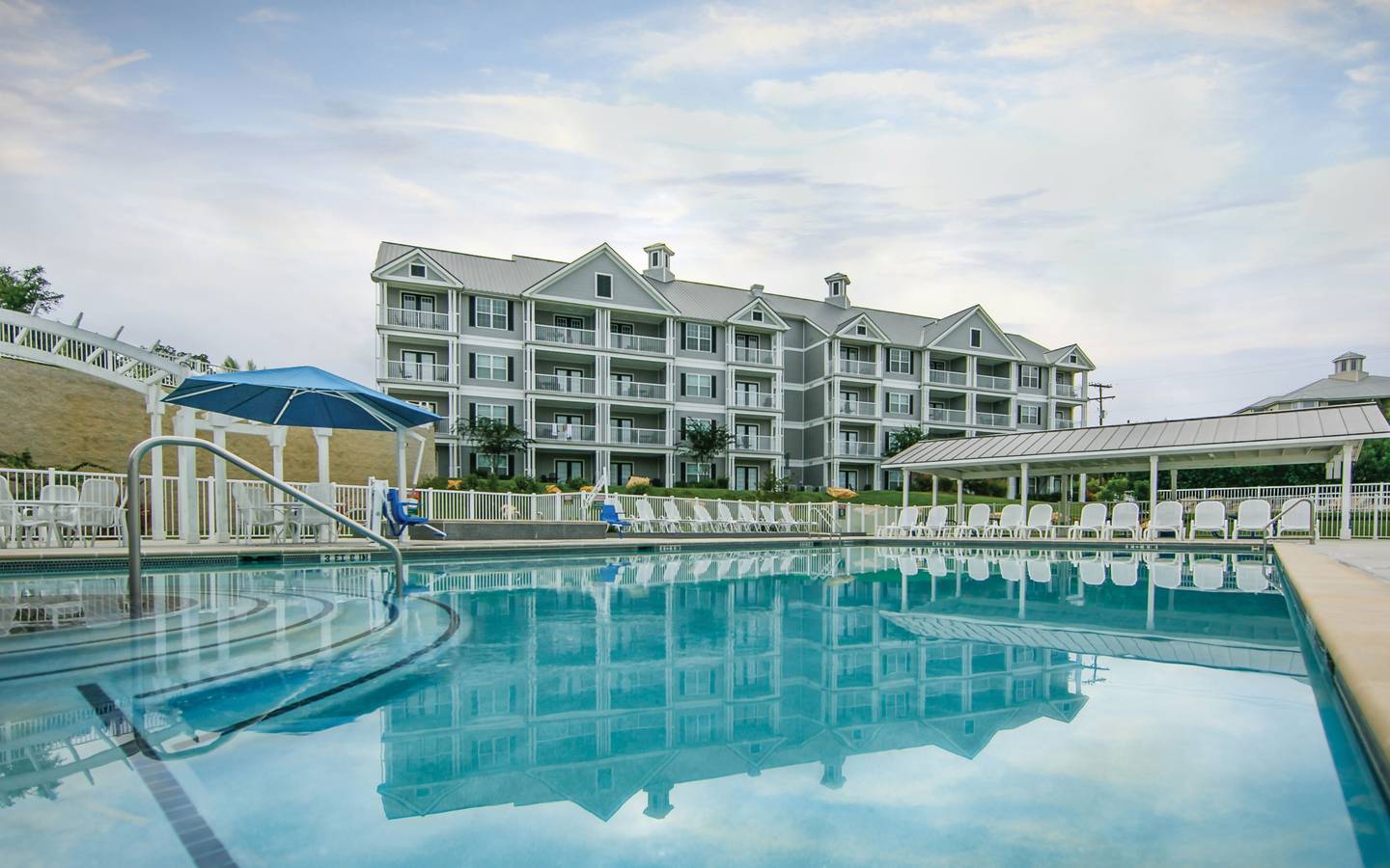 Outdoor pool and sun chairs with view of property building at Hill Country Resort in Canyon Lake, Texas