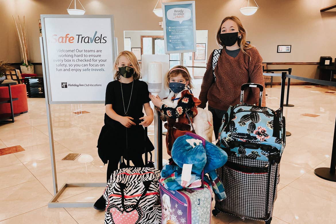 The Haby family poses with suitcases and masks near a 'Safe Travels' sign located in the lobby at our Desert Club Resort located in Las Vegas, Nevada.