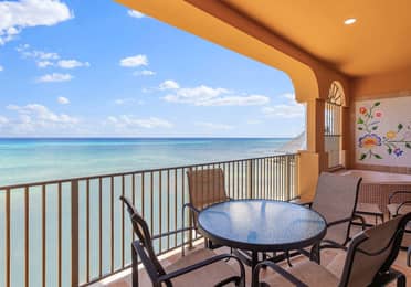 Oceanfront balcony with table, chairs, and soaking tub.