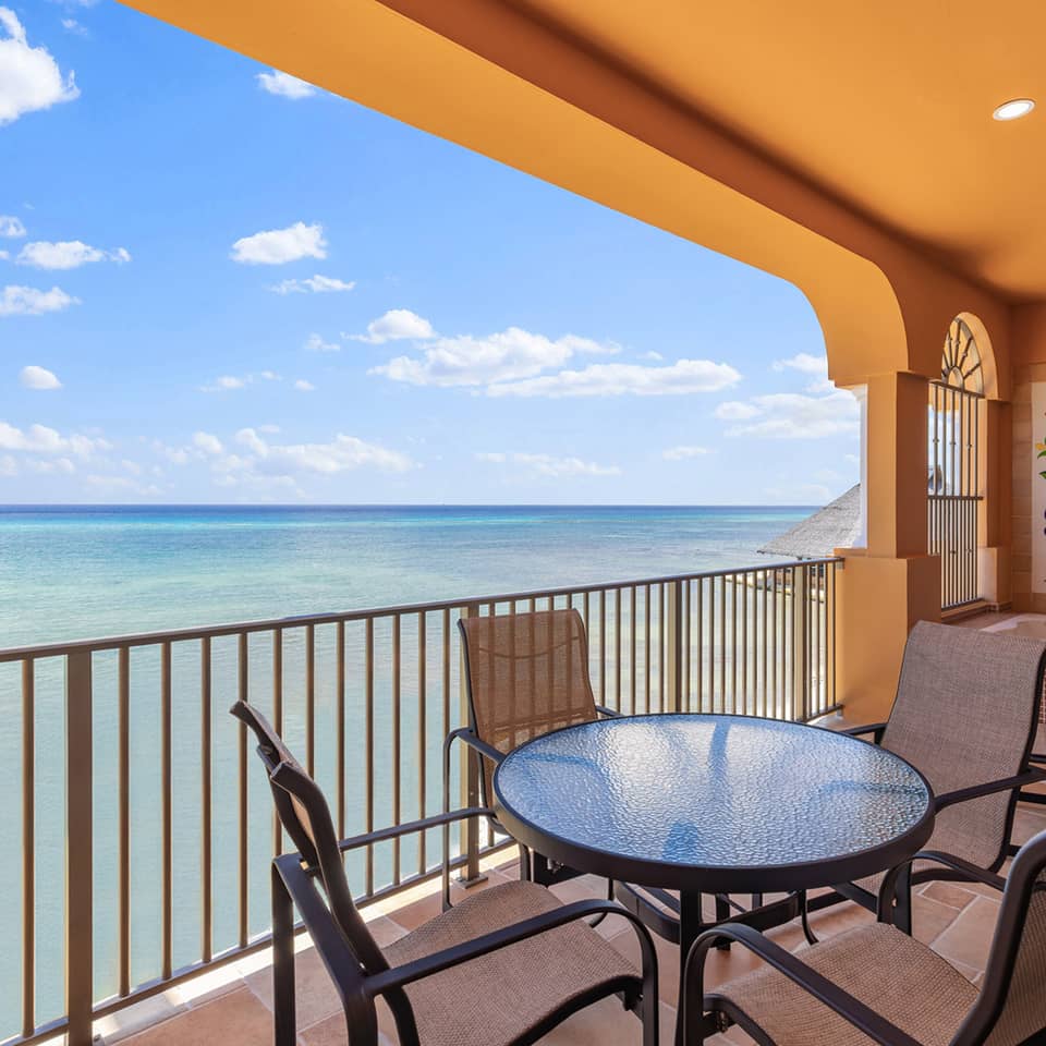 Oceanfront balcony with table, chairs, and soaking tub.