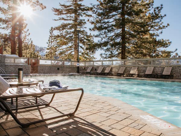 Outdoor pool surrounded by trees and pool chairs at Tahoe Ridge Resort in Stateline, Nevada.