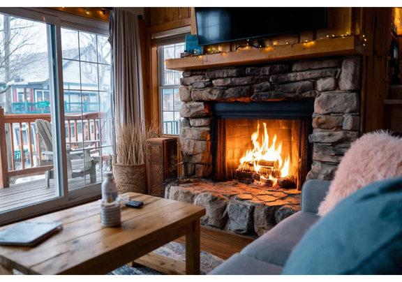 Comfortable indoor scene featuring a warm fireplace, cozy seating, and rustic dƩcor.