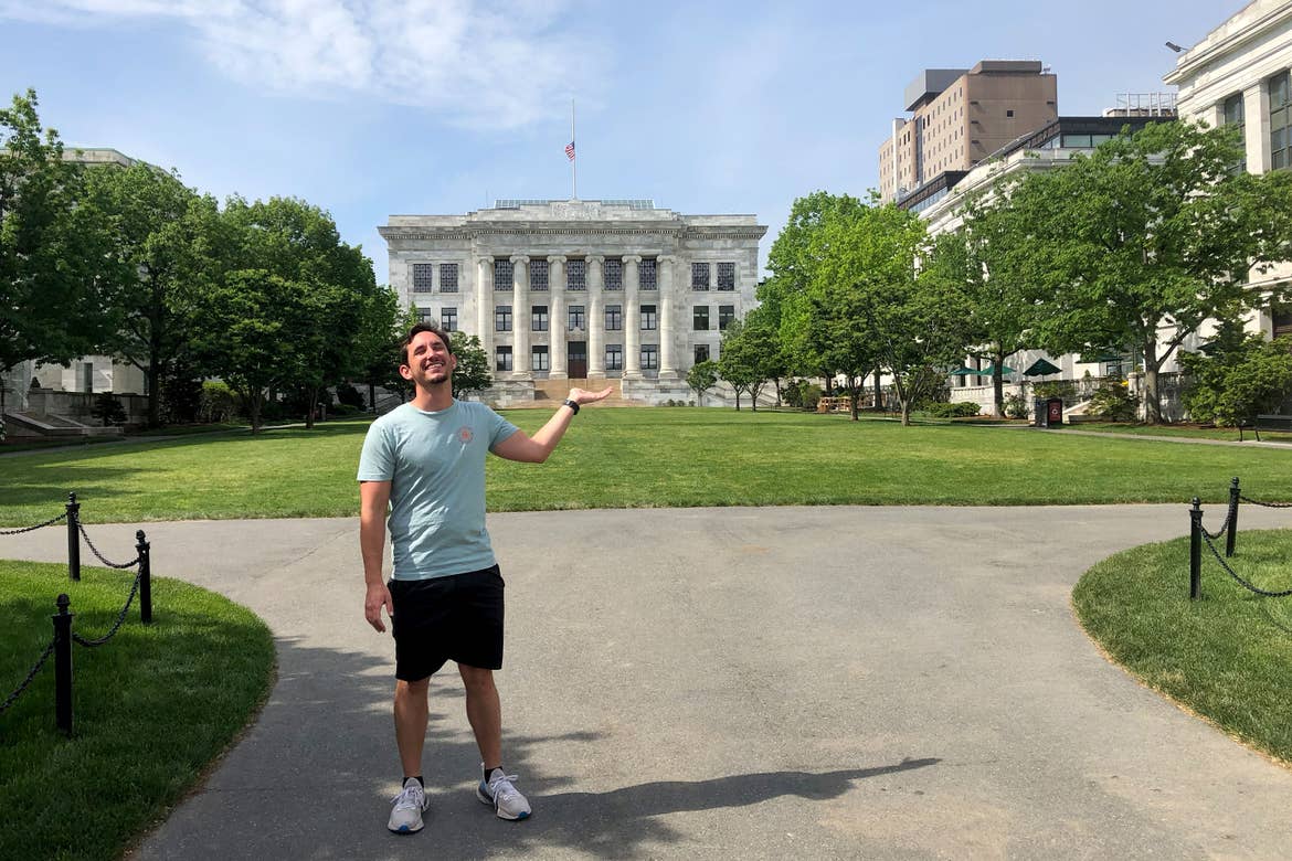 A man wears a t-shirt and shorts outside of Harvard University.