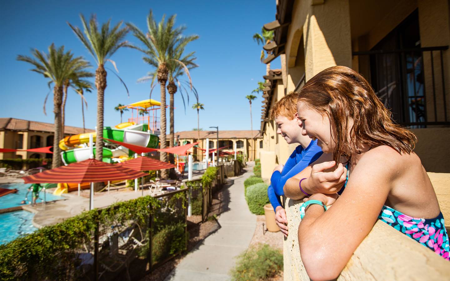 Two kids looking at outdoor pool from their villa balcony at Scottsdale Resort.