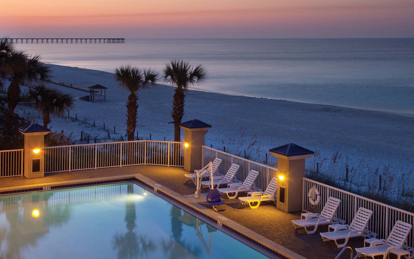 View of outdoor pool looking onto beach at sunset at Panama City Beach Resort in Florida.
