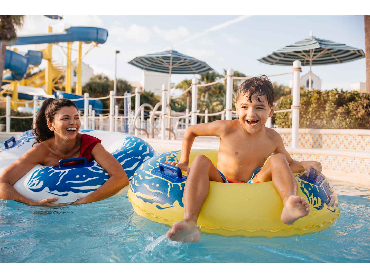 Mother and son float in tubes on water at water park.