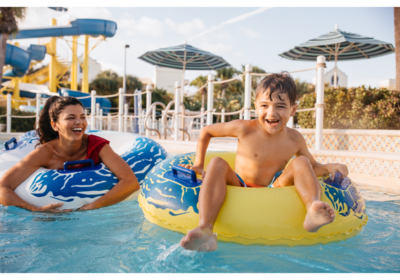 Mother and son float in tubes on water at water park.