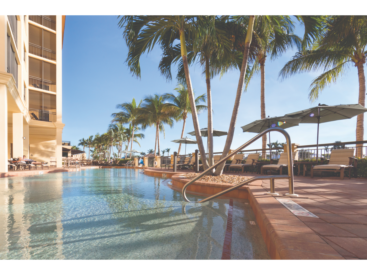 Pool at Sunset Cove Resort with loungers, palm trees, and a relaxing tropical setting.