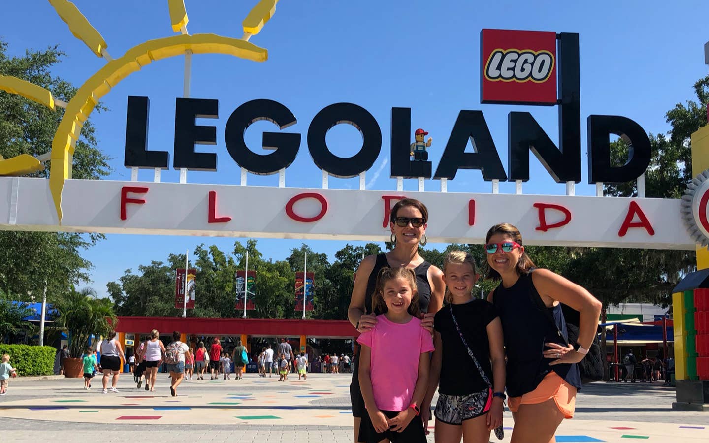 Two women (back) and two young girls (front) stand in front of a LEGOLAND sign in Orlando.