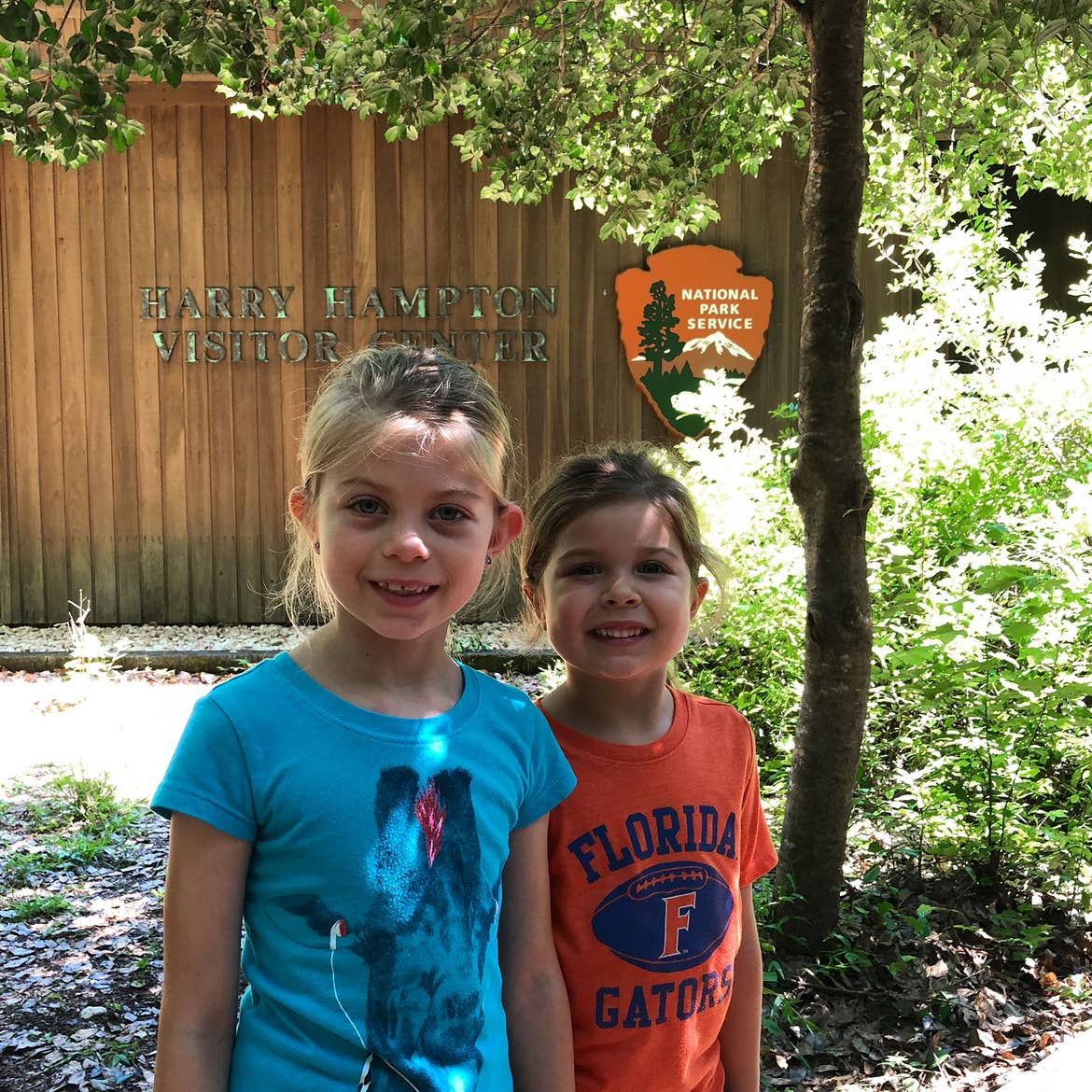 Author, Chris Johnstons' daughters, Kyndall (left), and Kyler (right) pose with a sign that reads, 'Harry Hampton Visitor Center, National Park Service.'