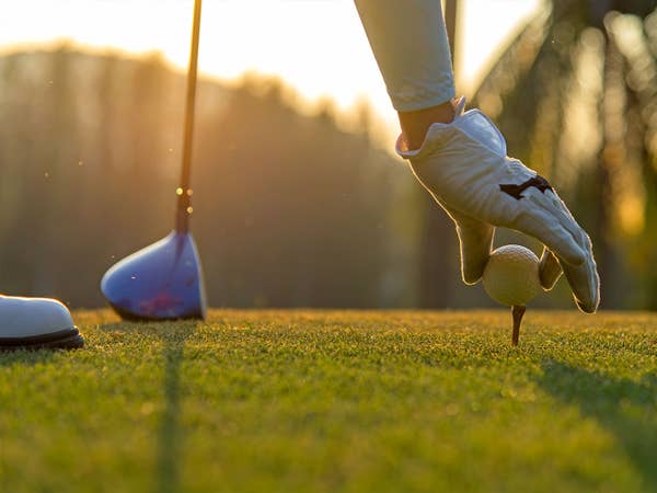 Golfer putting ball on tee