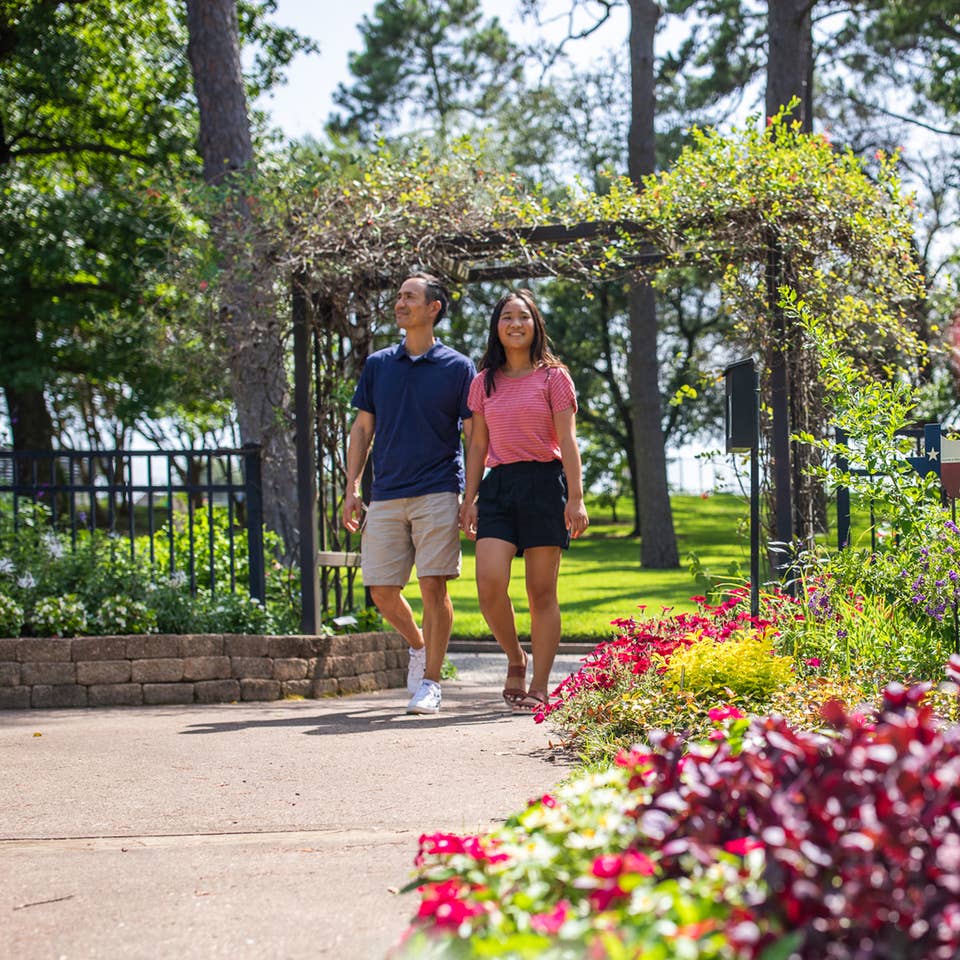 Two people walking through Tyler Rose Garden near Villages Resort in Flint, Texas.