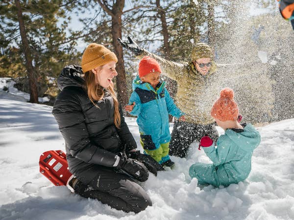 Dad throwing snow above two children on snowy mountain near Tahoe Ridge Resort in Stateline, Nevada.