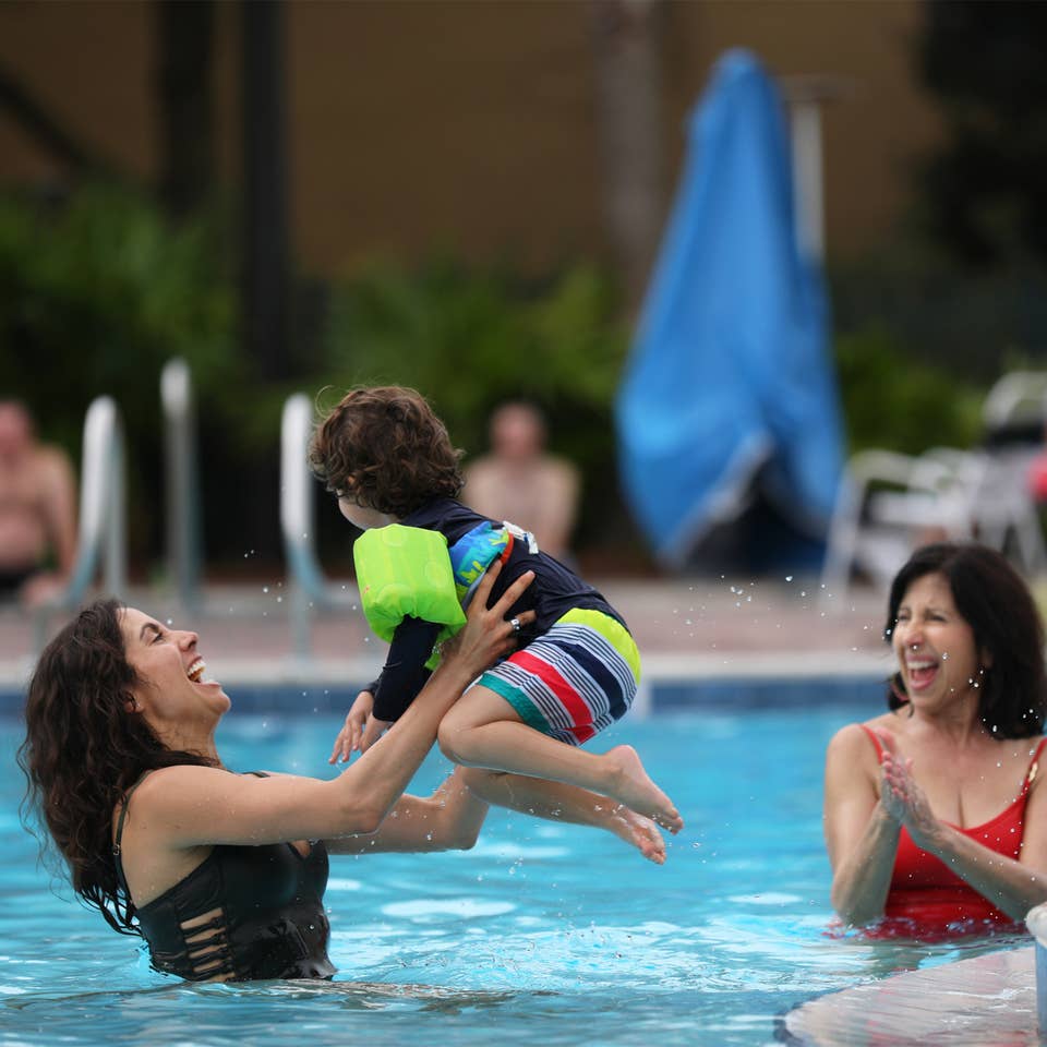 Mother playing with child in outdoor pool.