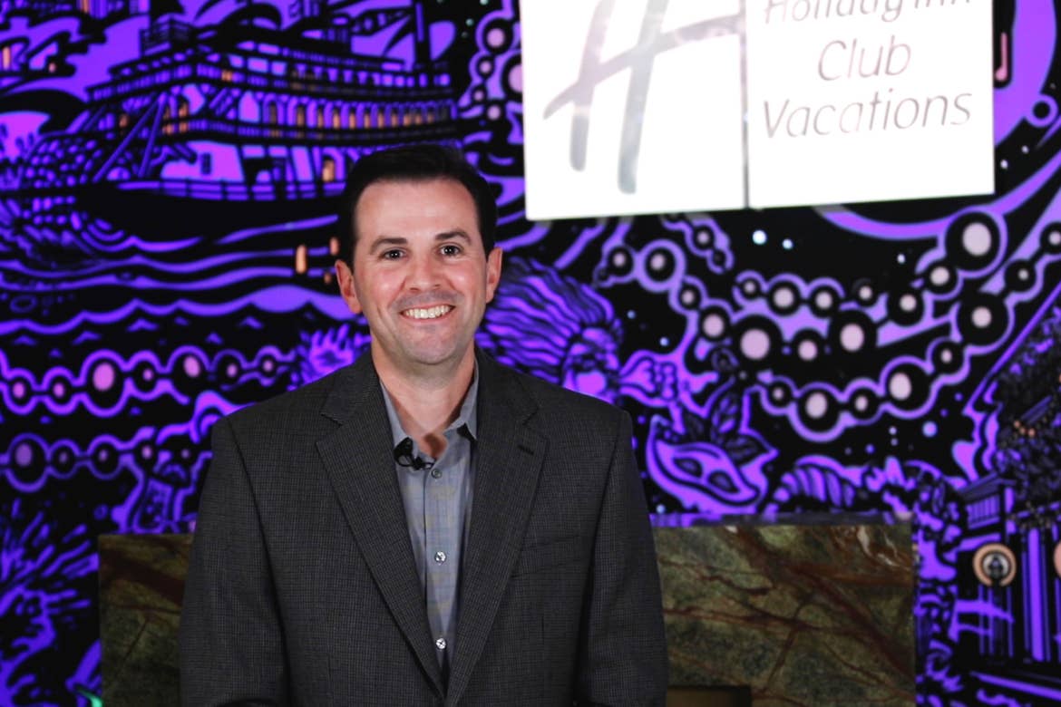 General Manager, Mike Larose, wears a black suit while standing in front of our animated mural projection in the lobby of our New Orleans resort in Louisiana.