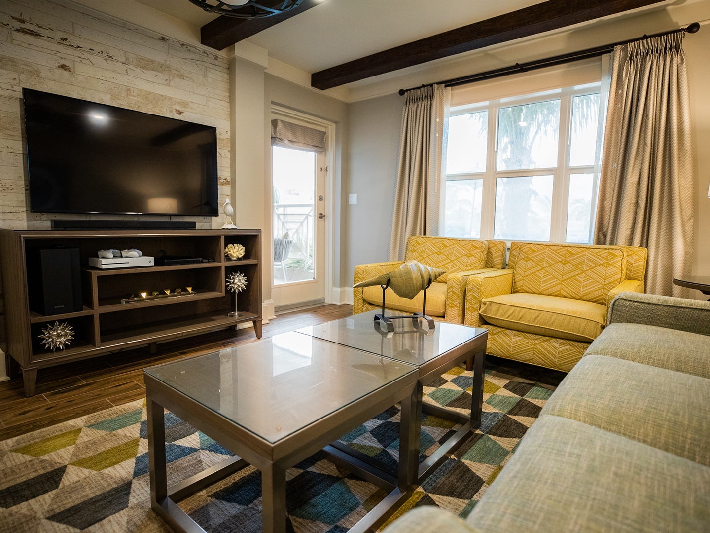 Living room with couch, two chairs and a flat screen TV in a two-bedroom Signature Collection villa at Cape Canaveral Beach Resort.
