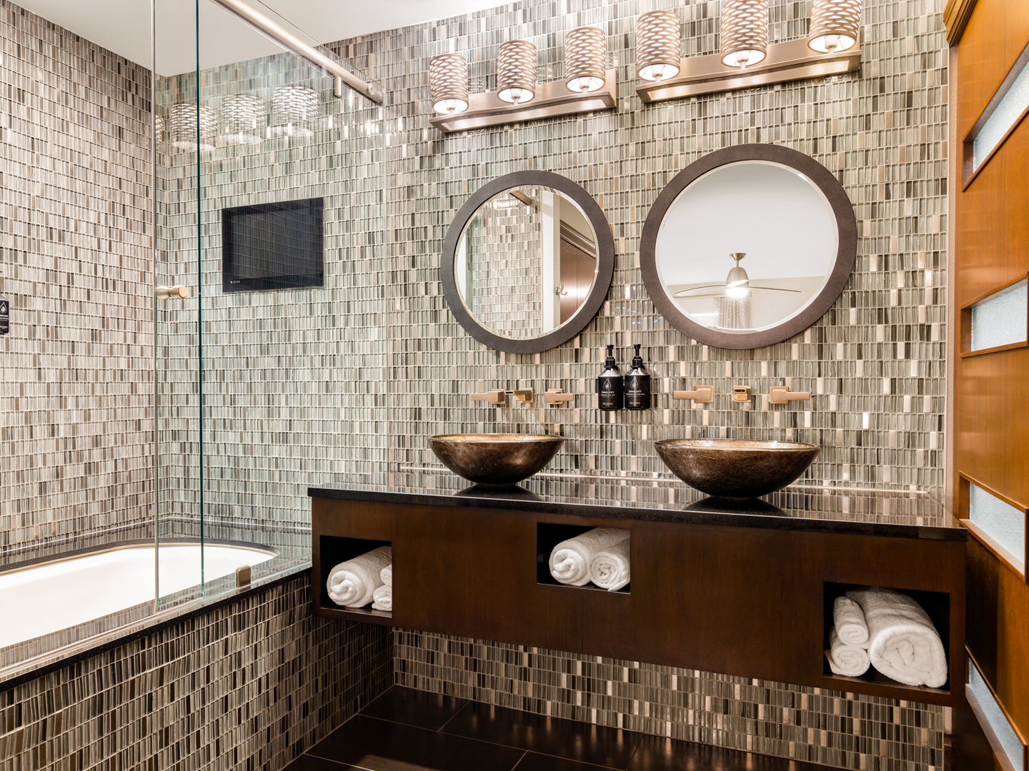 Elegant bathroom with dual sinks and mosaic tile walls.
