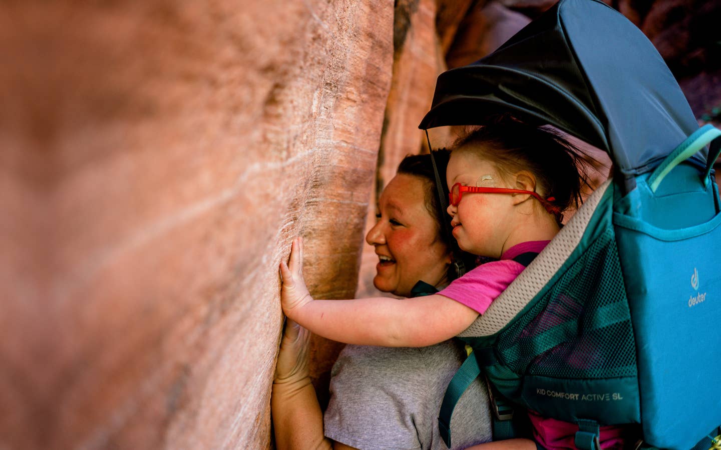 Featured Contributor, Melody Forsyth (left), backpacks with her daughter, Ruby (right), as they touch some rock formations.