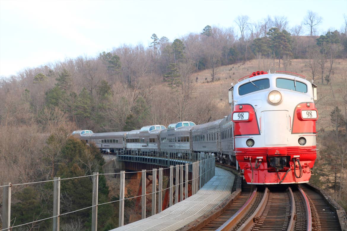 A Zephyr Scenic train in red approaches the foreground on it's tracks.