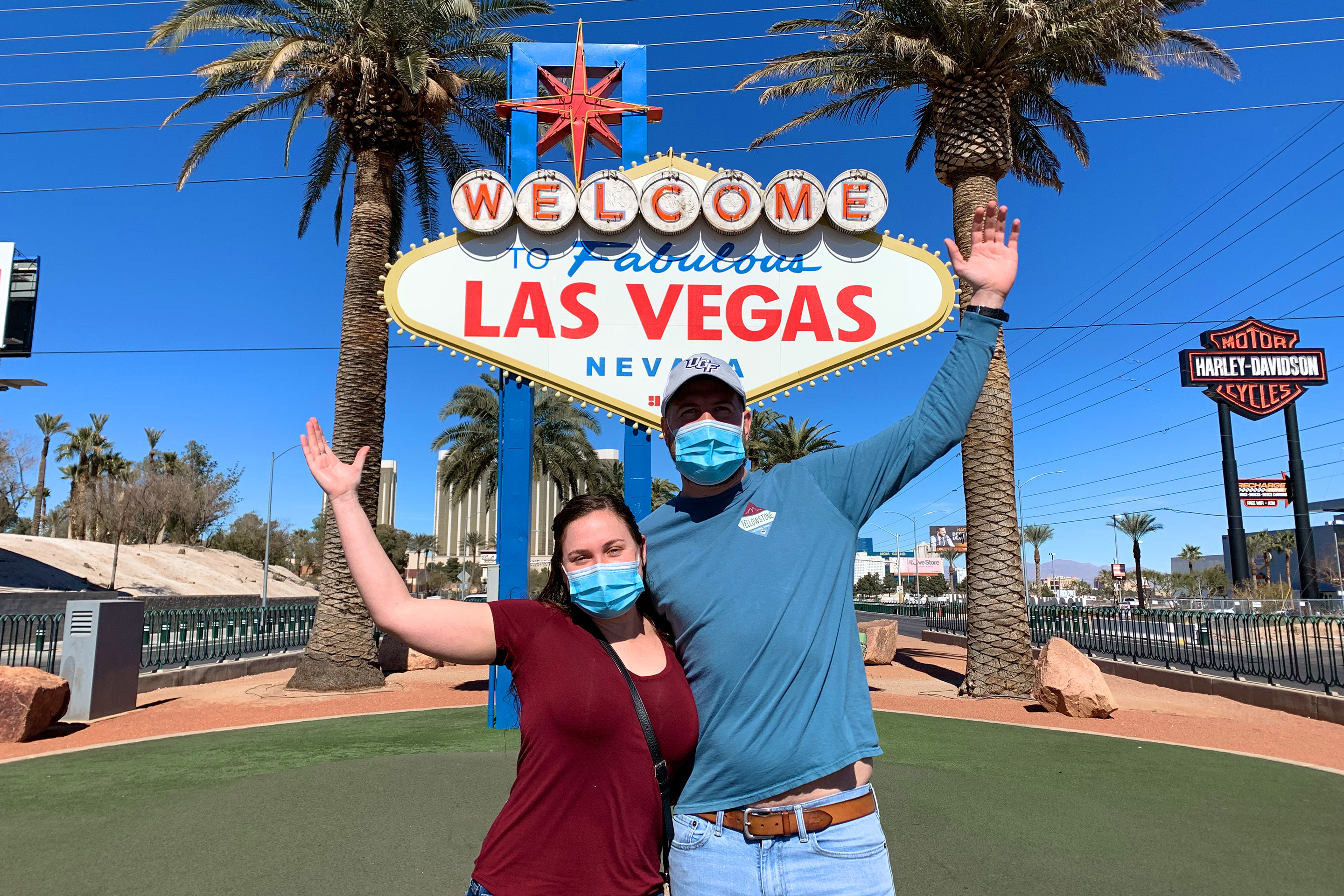 Featured Contributor, Ashley Fraboni (left) and her fiancé, Nicholas (right), pose in front of the 'Welcome to Las Vegas' marquee while wearing face masks.