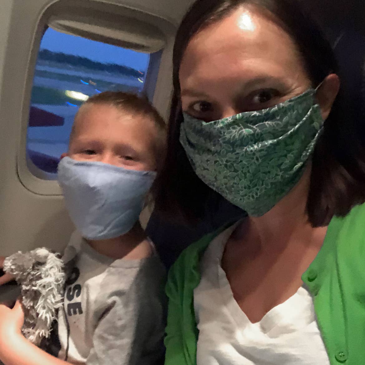 Author, Sarah, and son, Logan, sit near the window seat on their airplane wearing masks for safety.