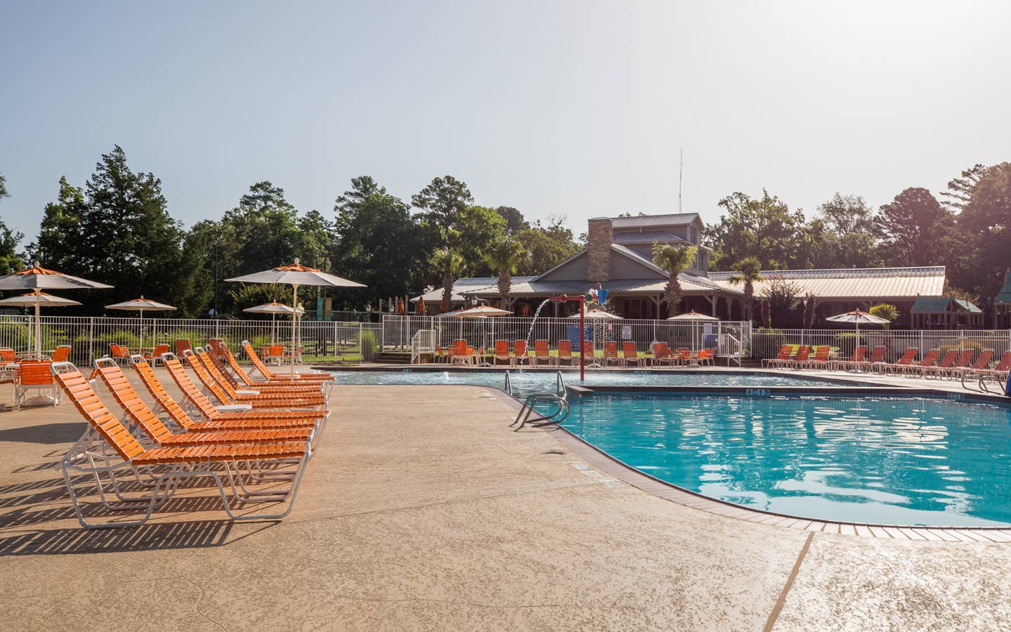 Outdoor pool with orange pool chairs surrounding it at Villages Resort in Flint, Texas.
