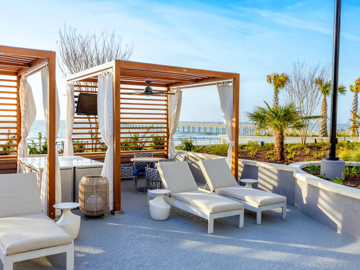 Circular pool with lounge chairs surrounding and ocean in distance.