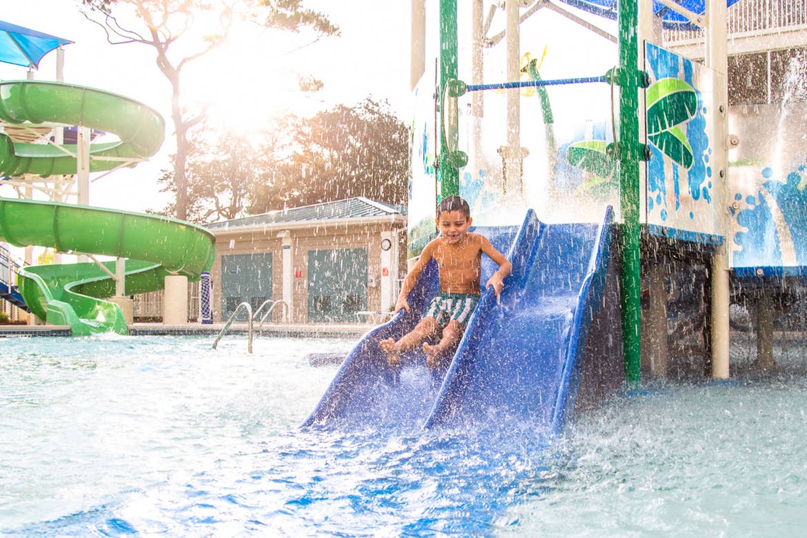 Author, Brenda Rivera Stearns' son slides down a blue slide into the pool at Splash Cove at our South Beach resort in Myrtle Beach, South Carolina.