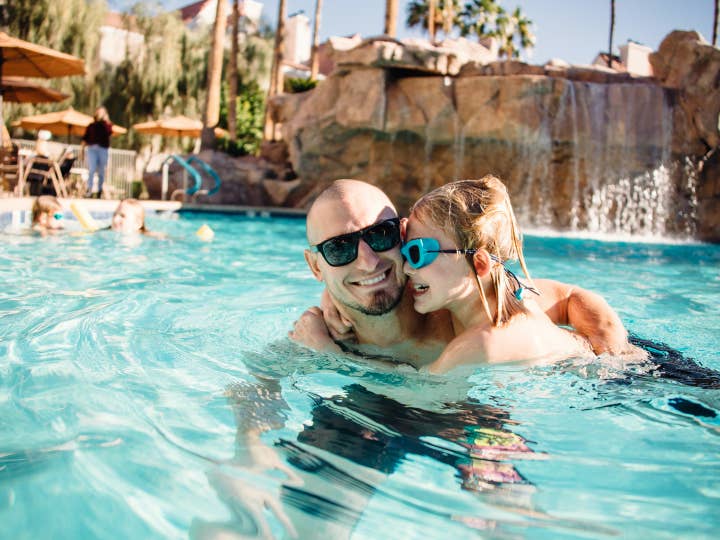 Dad and daughter in Watering Hole pool with fountain at Desert Club Resort in Las Vegas, Nevada.