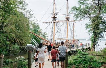 A family walks towards the Susan Constant ship at Jamestown Settlement in Williamsburg, Virginia.