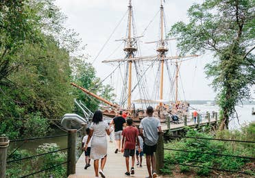 A family walks towards the Susan Constant ship at Jamestown Settlement in Williamsburg, Virginia.