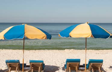 View of four beach chairs under two umbrellas at Panama City Beach in Florida.