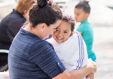 Adult hugging young child wrapped in towel by outdoor pool at Holiday Hills Resort in Branson, Missouri.