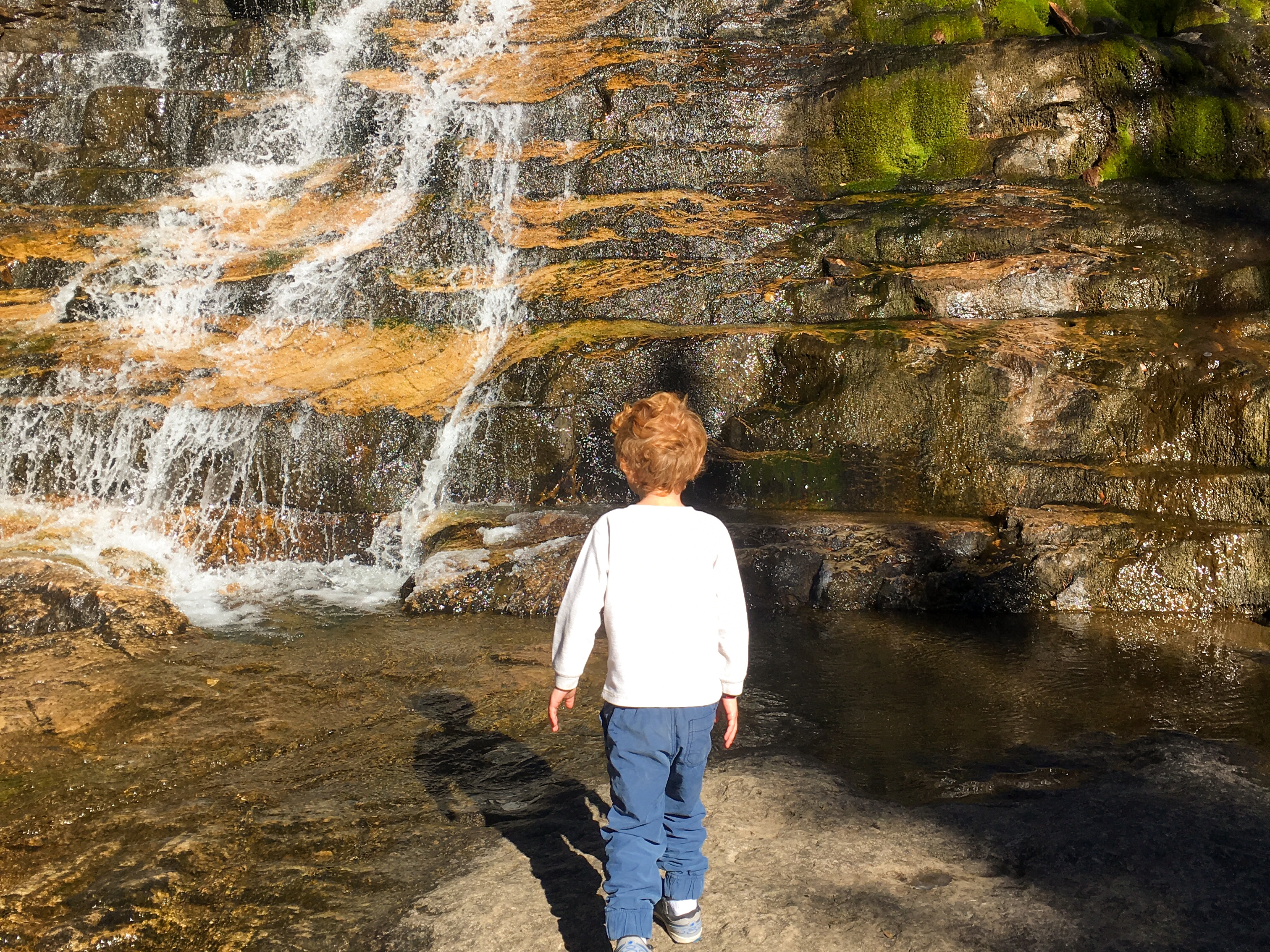 Jessica's son walking toward a small cascading waterfall