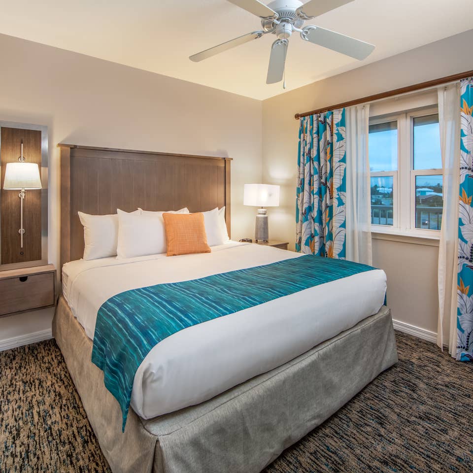 Bedroom with large window with view of ocean and ceiling fan in a two-bedroom villa at Panama City Beach Resort