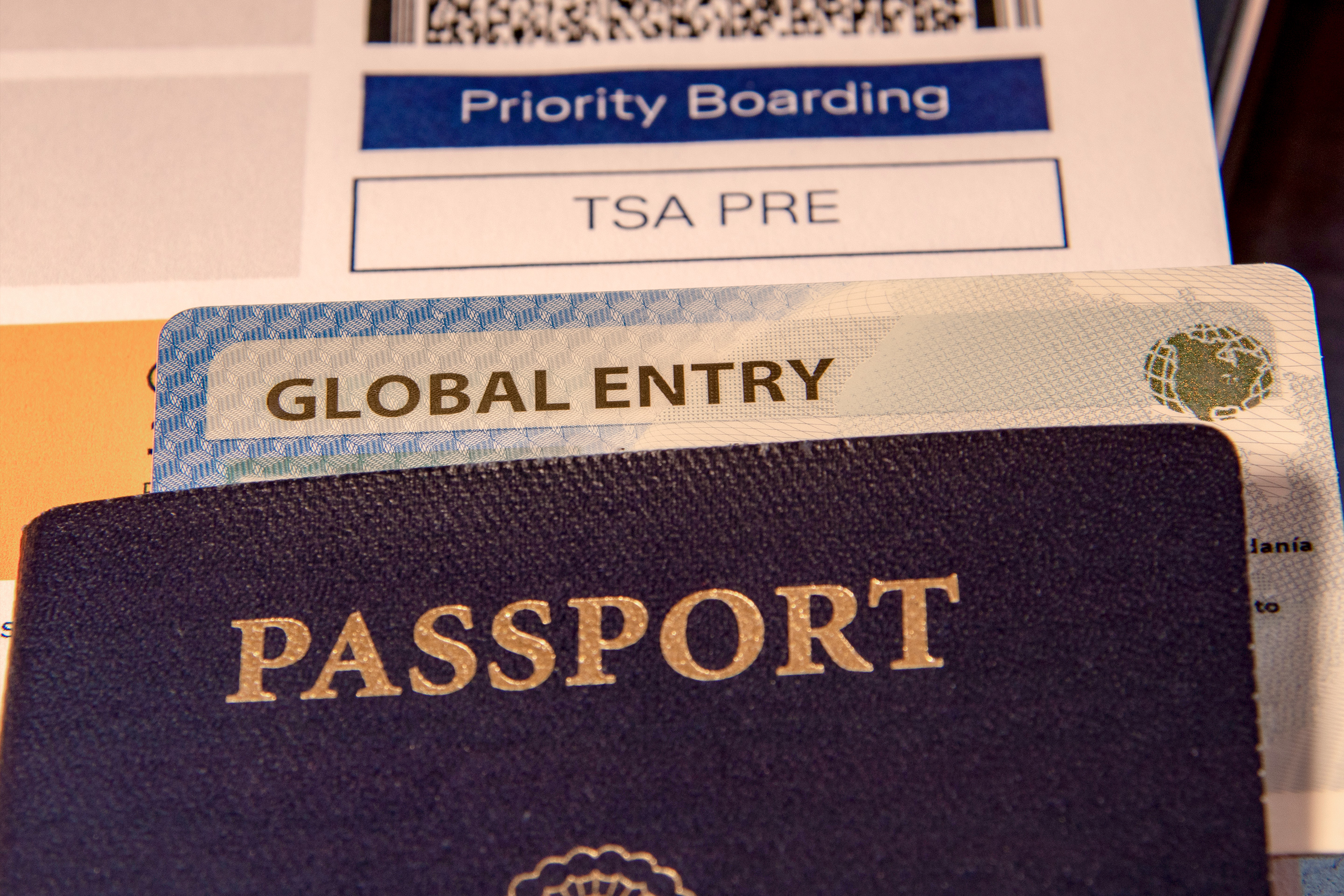 A passport cover placed on top of a ticket with 'global entry' notation and a boarding pass that reads, 'TSA PRE.'