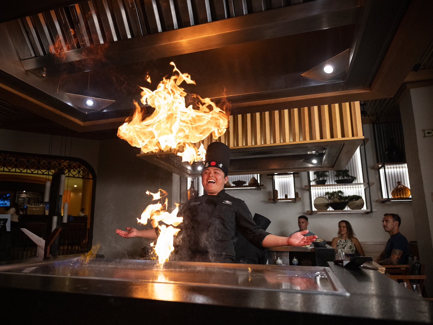 Man cooking on a hibachi grill with flames at Kinoko at Royal Haciendas Resort in Mexico.