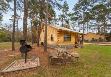 Cabin with BBQ and picnic tables at the Lake O' the Wood Resort in Flint Texas.