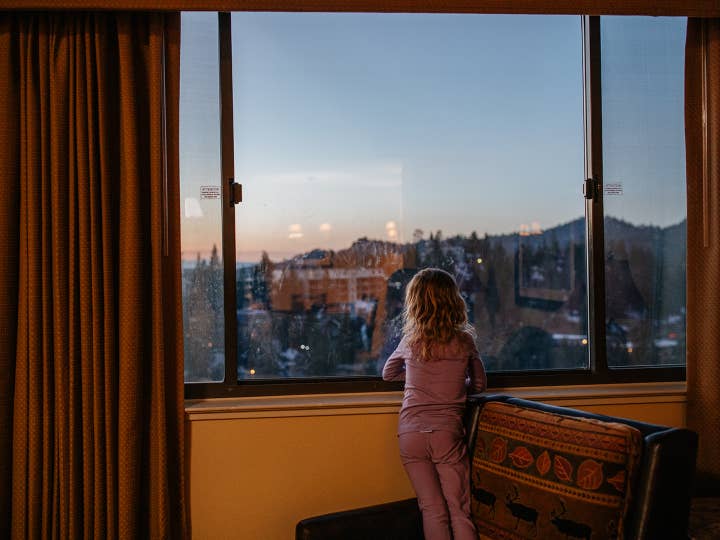 Small child looking out window to view Sierra Nevada Mountains at Tahoe Ridge Resort in Stateline, Nevada.