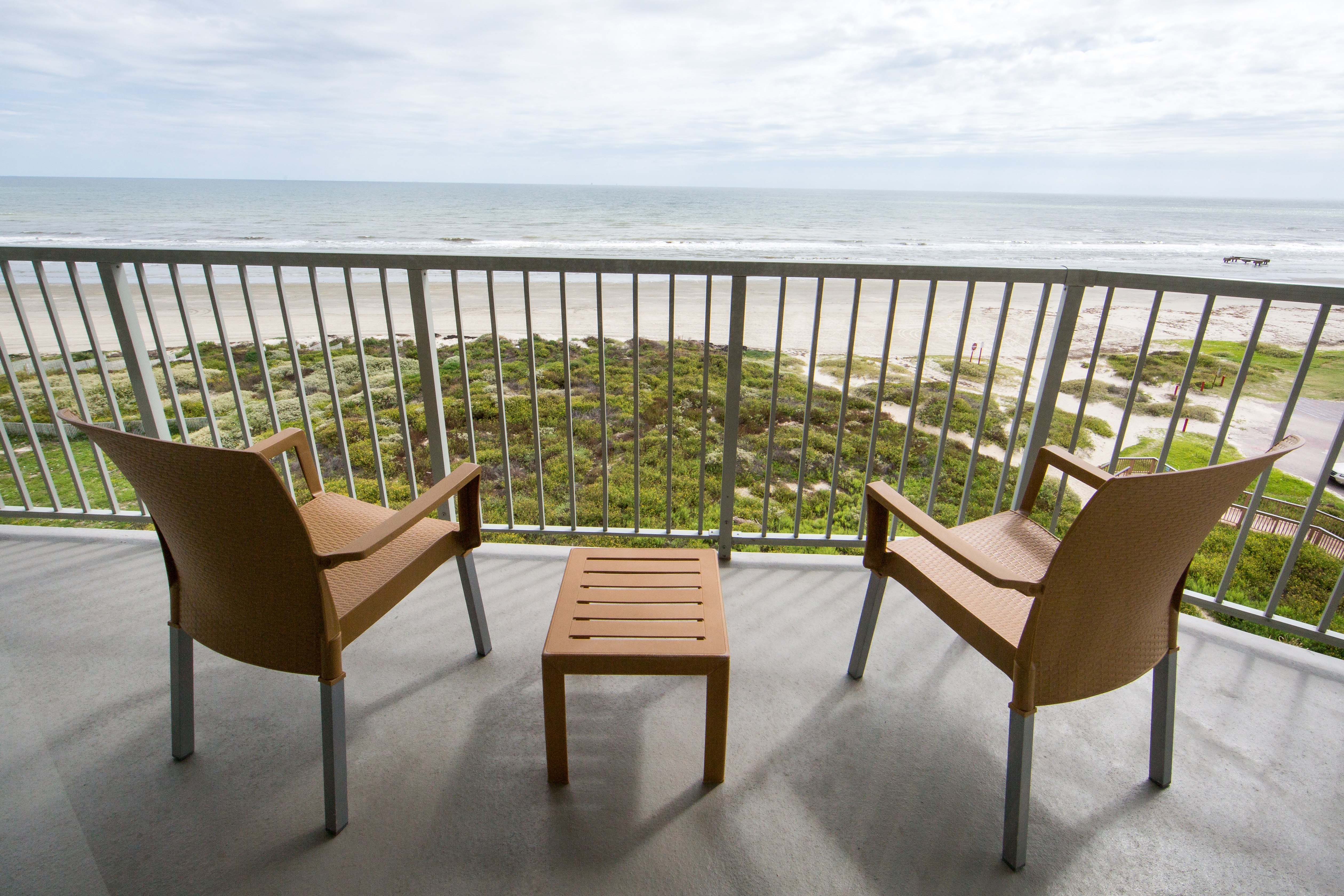 Furnished balcony with two chairs overlooking the beach in a two-bedroom villa at Galveston Beach Resort
