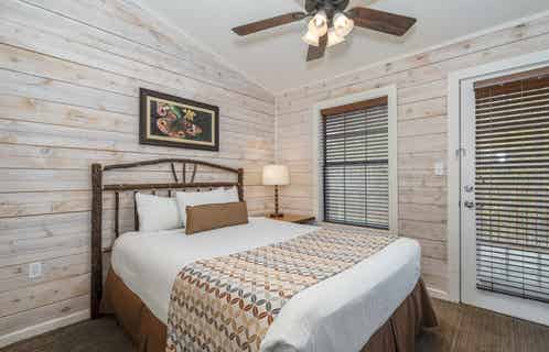 Bedroom with queen bed and ceiling fan in a two bedroom cabin at Piney Shores Resort in Conroe, Texas